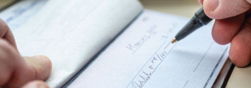 Close-up of someone writing a check with a pen.