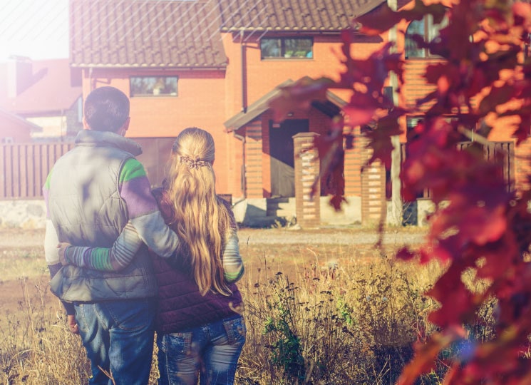 Couple standing outside new house financed by home loans in Eastern Iowa