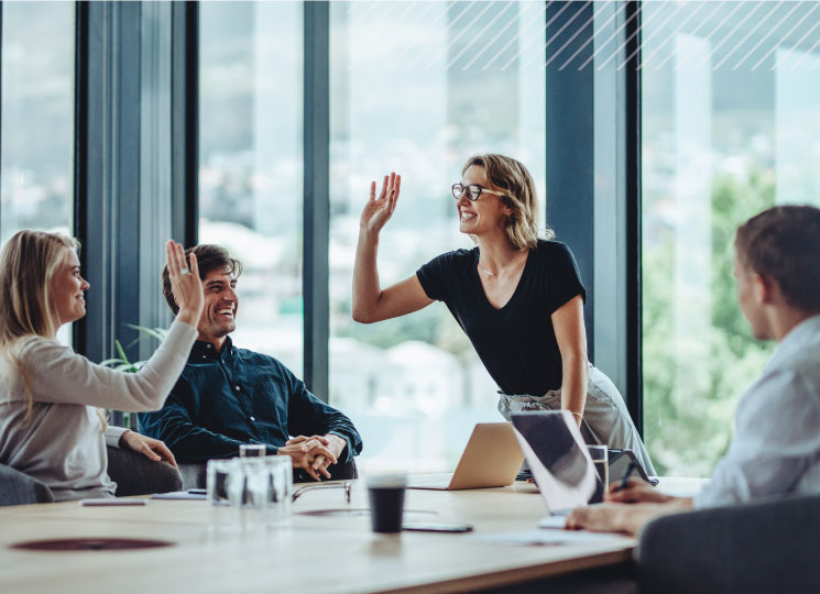 Business professionals celebrating success with a high five during a team meeting in an office