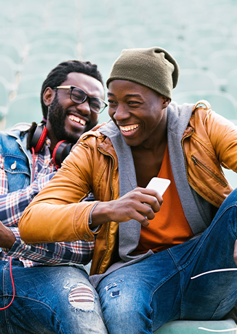 Two friends laughing outdoors while one holds a phone, representing FSB’s Refer a Friend program.