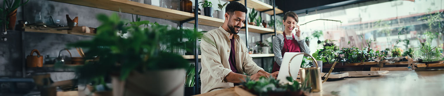 People in a plant shop smiling while working on a computer