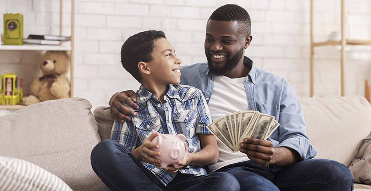 Dad teaching his son financial literacy and the importance of saving.