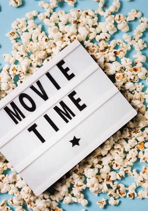 sign that reads "Movie Time" sitting in a pile of popcorn